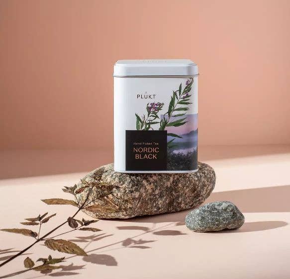 Tea canister labeled 'Nordic Black' by PLöKT on a stone with a natural background