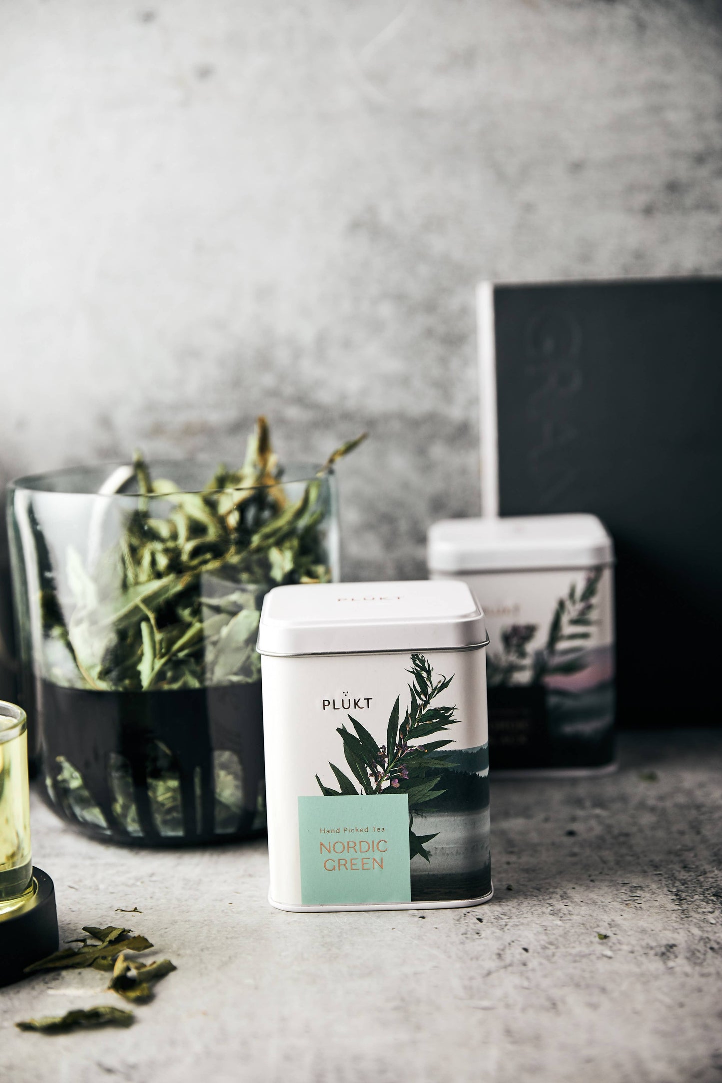Tea canisters with botanical labels on a gray surface