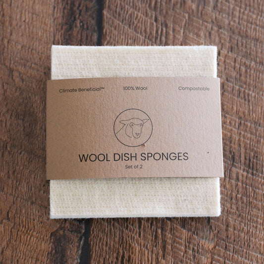 Set of wool dish sponges with a cardboard packaging on a wooden surface