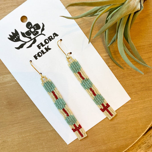 Beaded earrings on a Flora Folk branded card with a plant in the background