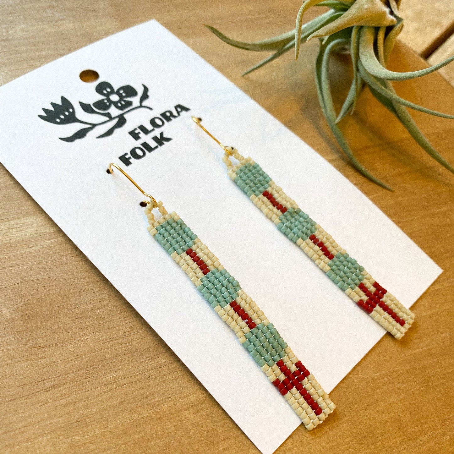 Beaded earrings on a Flora Folk branded card with a plant in the background