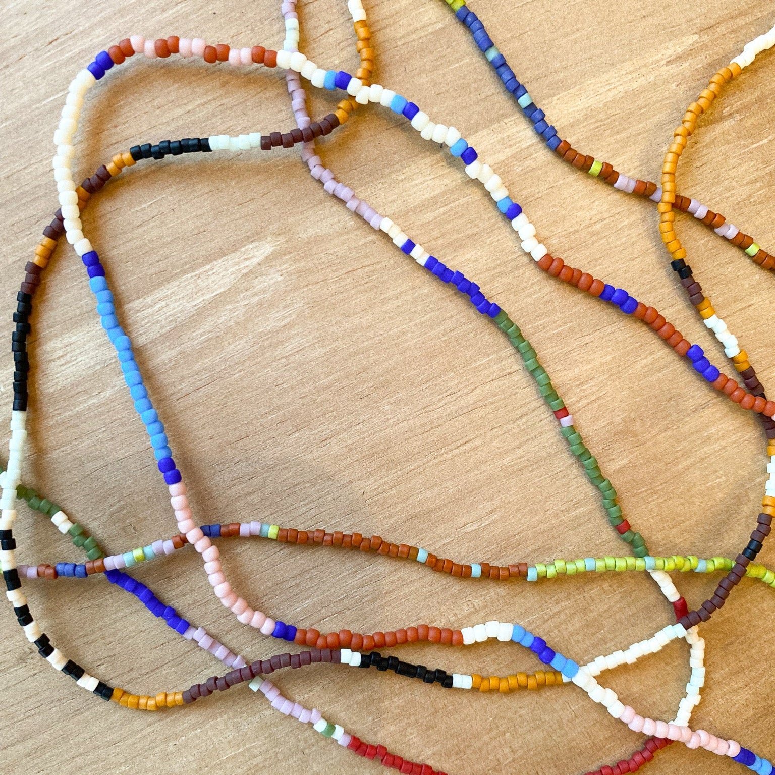 Colorful beaded necklaces on a wooden surface