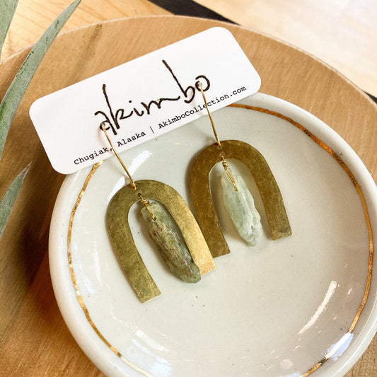Pair of green stone earrings on a white dish with 'akimbo' branding.
