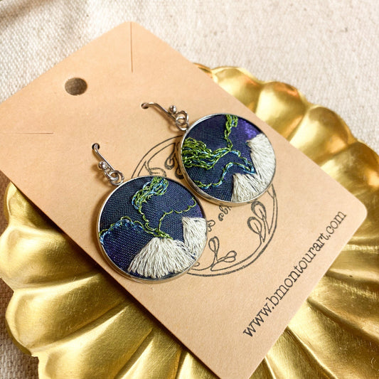 Pair of earrings on a gold dish with a branded card