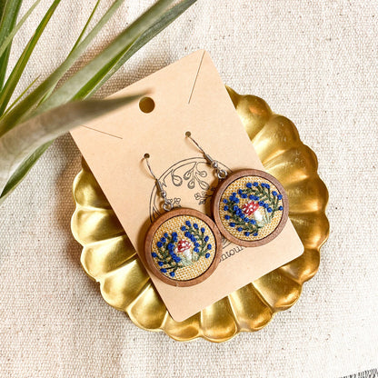 Wooden earrings with floral design on a gold stand with a beige background