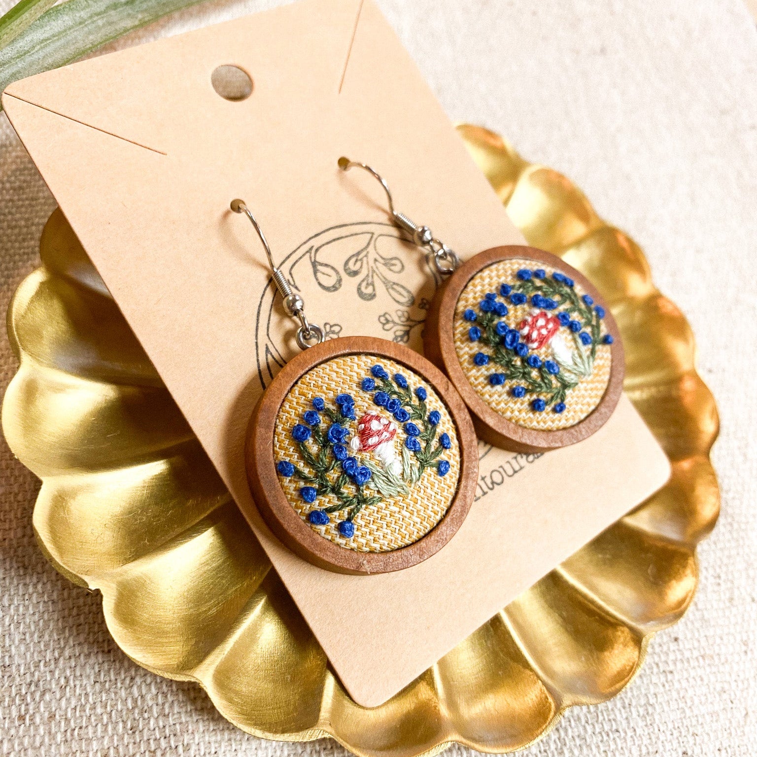 Wooden earrings with floral designs on a gold stand with a beige card.