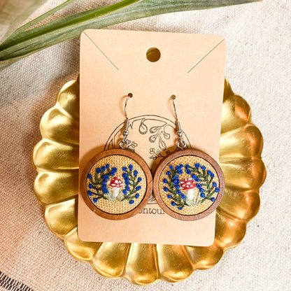 Pair of mushroom earrings on a decorative card on a cold tray.