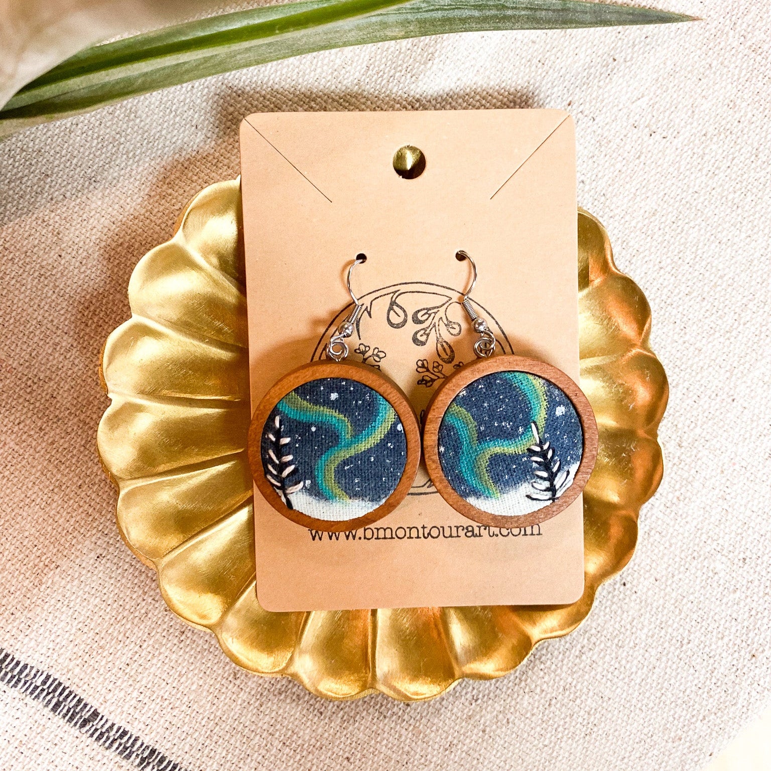 Wooden earrings with a starry night design on a gold stand with a beige background
