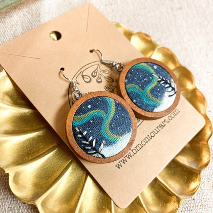 Wooden earrings with blue and green design on a gold stand with a beige card.