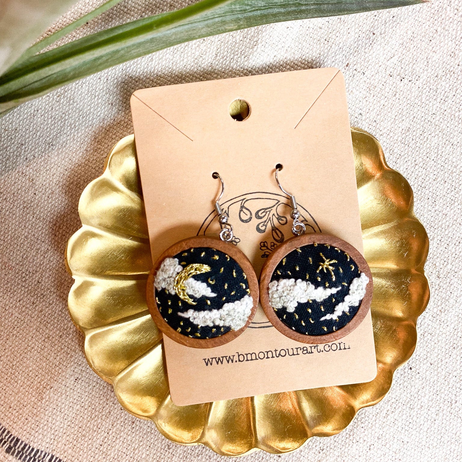 Wooden earrings with a celestial design on a gold dish with a branded card.