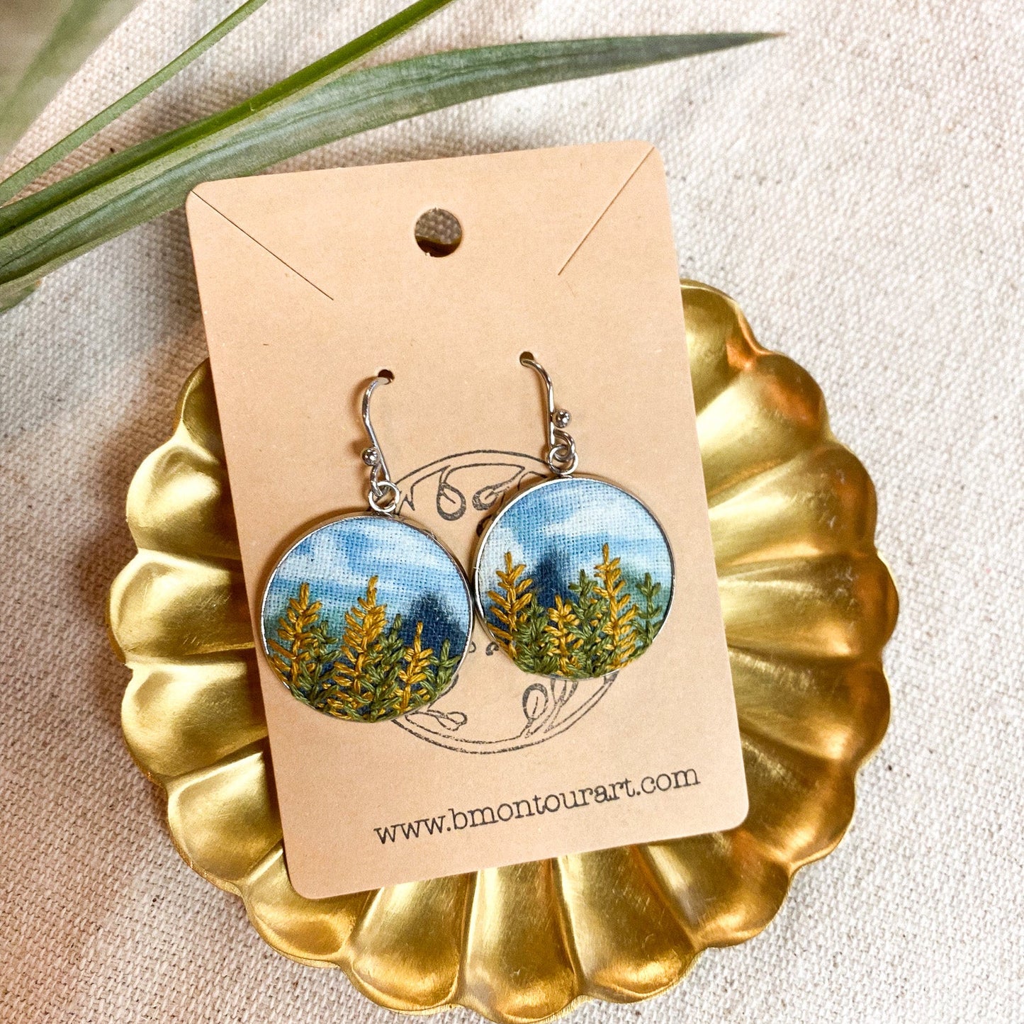 Earrings with nature-themed design on a gold stand and beige card