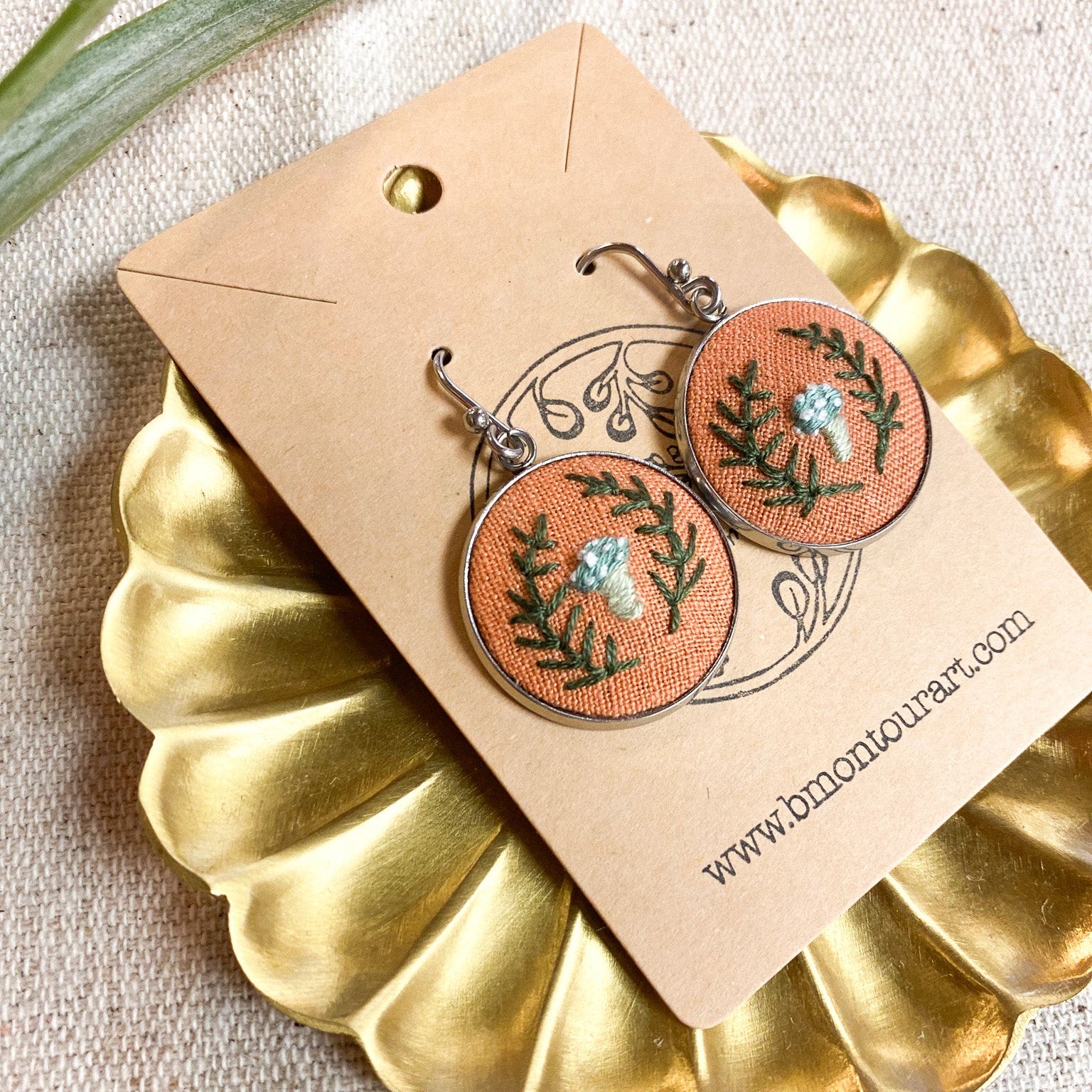 Pair of earrings on a branded card with a gold scalloped edge