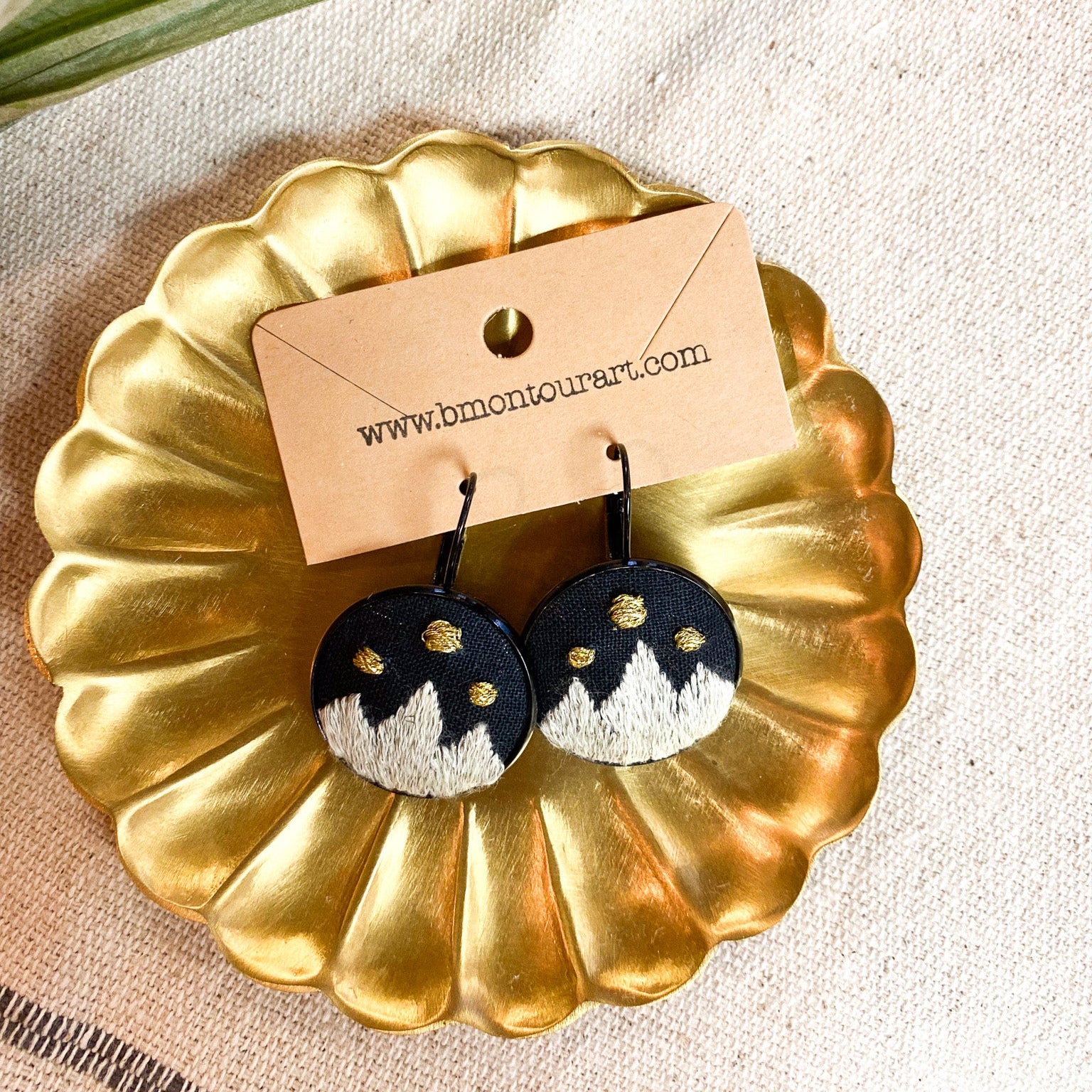 Pair of earrings on a gold display stand with a branded card