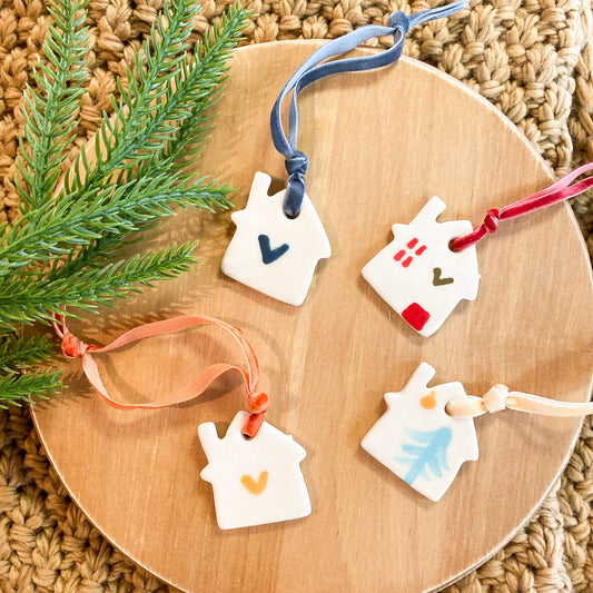 Decorative house-shaped ornaments on a wooden board with greenery