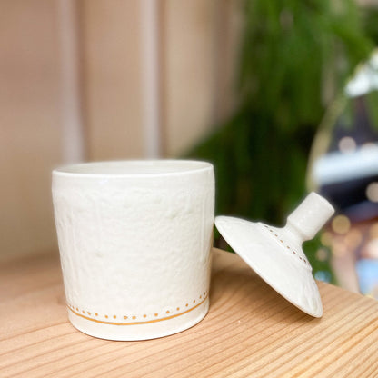 White textured candle jar with lid on a wooden surface