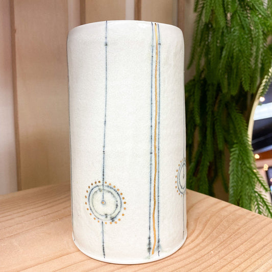 Cylindrical ceramic vase with decorative patterns on a wooden surface