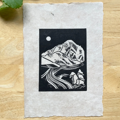 Black and white mountain illustration on a textured paper with green leaves in the corner.