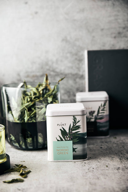 Tea canisters with botanical labels on a gray surface