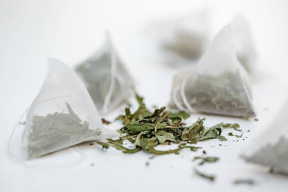 Tea bags with loose tea leaves on a white background