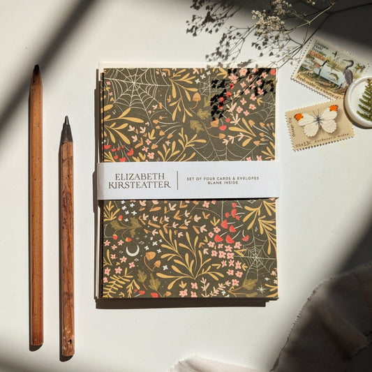 Set of four floral cards and envelopes by Elizabeth Kirsteatter on a light surface with a pen and decorative items.