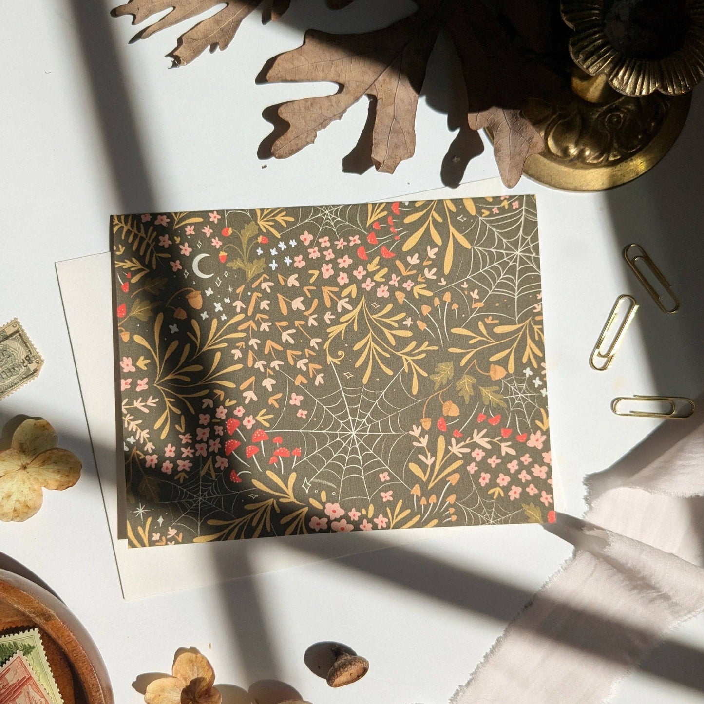 Decorative paper with spider web and floral pattern on a white surface with decorative items.