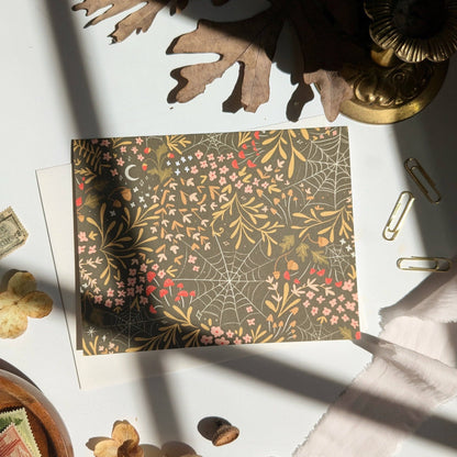 Decorative paper with spider web and floral pattern on a white surface with decorative items.